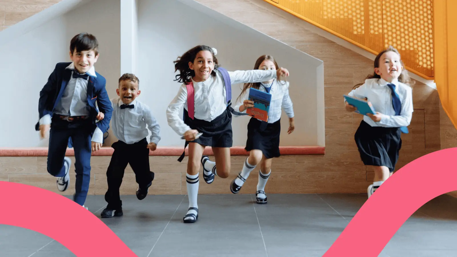Niños con uniforme escolar corriendo y sonriendo por un pasillo